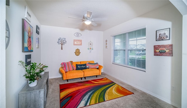 living area with ceiling fan and carpet