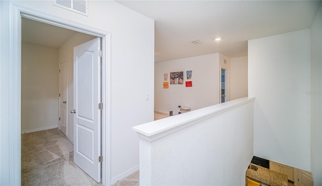 corridor featuring baseboards, visible vents, light carpet, and an upstairs landing