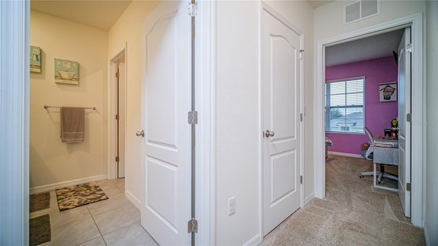 corridor featuring light tile patterned flooring, light colored carpet, visible vents, and baseboards