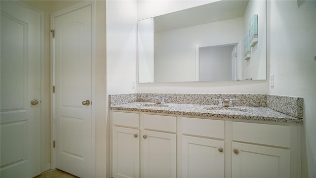 bathroom featuring double vanity, a closet, and a sink
