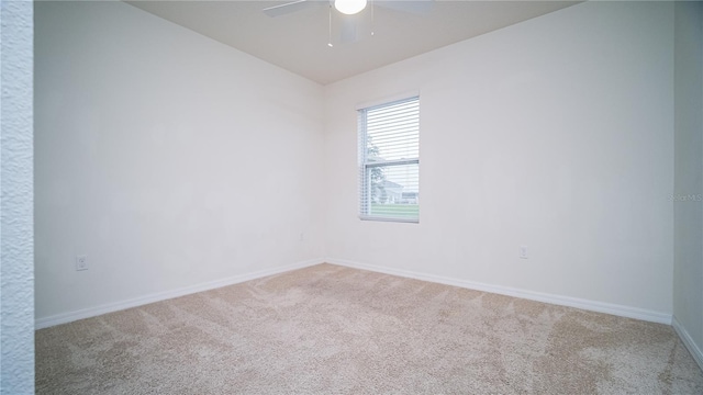 carpeted spare room featuring baseboards and a ceiling fan