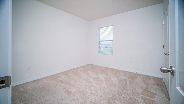 empty room featuring light carpet and baseboards
