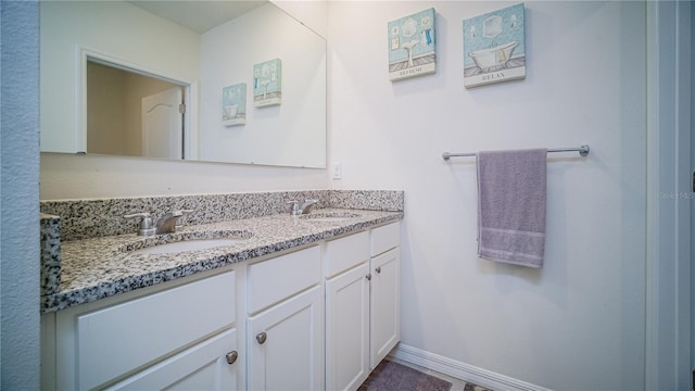 full bathroom with double vanity, baseboards, and a sink