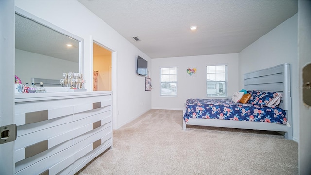 bedroom with light carpet, visible vents, and a textured ceiling