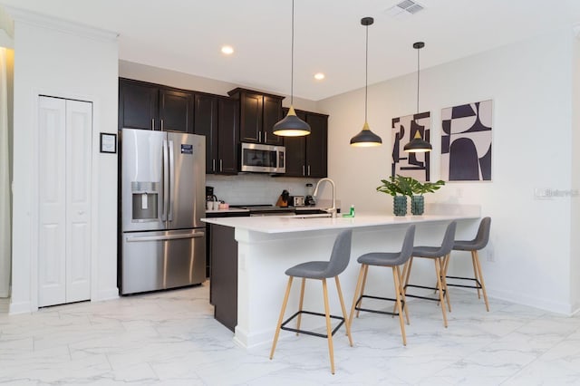 kitchen featuring sink, decorative light fixtures, appliances with stainless steel finishes, a kitchen breakfast bar, and backsplash