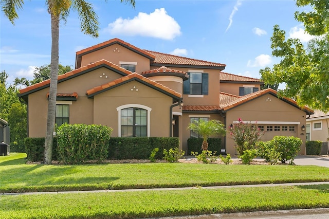 mediterranean / spanish house with an attached garage, a tiled roof, driveway, stucco siding, and a front yard