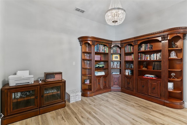 living area featuring wood finished floors, visible vents, and a notable chandelier