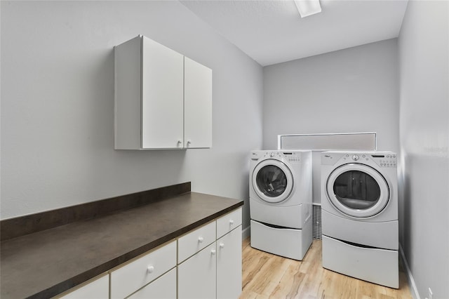 clothes washing area featuring light hardwood / wood-style floors, separate washer and dryer, and cabinets