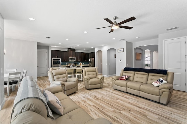 living room featuring recessed lighting, visible vents, arched walkways, and light wood finished floors