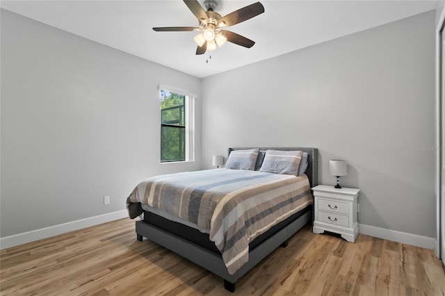 bedroom featuring a ceiling fan, light wood-style flooring, and baseboards