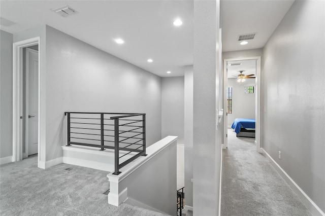 hallway with baseboards, carpet flooring, visible vents, and an upstairs landing