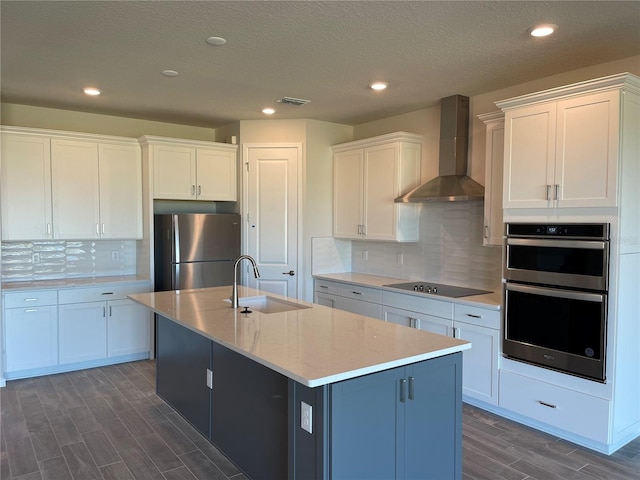 kitchen featuring sink, white cabinetry, stainless steel appliances, and wall chimney exhaust hood