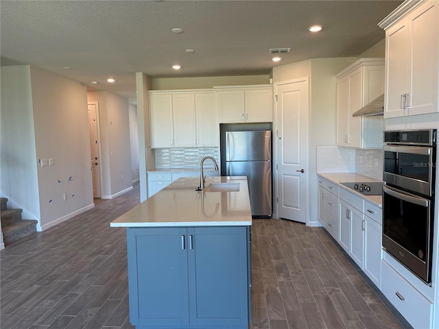 kitchen with sink, white cabinetry, stainless steel appliances, an island with sink, and decorative backsplash