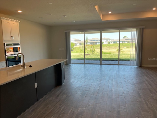 kitchen with hardwood / wood-style floors, white cabinetry, stainless steel double oven, and a wealth of natural light