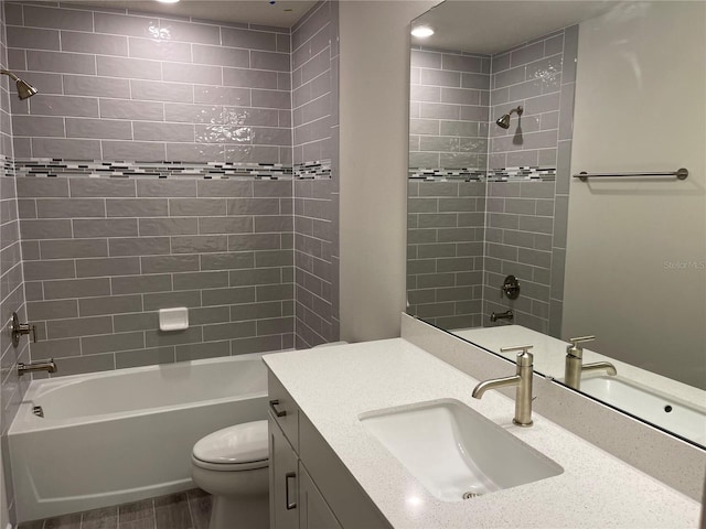 full bathroom featuring tiled shower / bath combo, vanity, and toilet