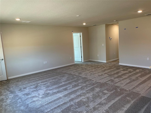 unfurnished room with dark carpet and a textured ceiling