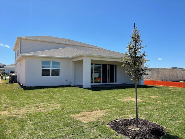 rear view of property with central AC and a yard