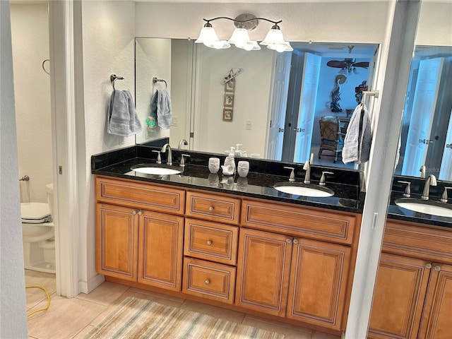 bathroom with tile patterned flooring, toilet, and dual bowl vanity