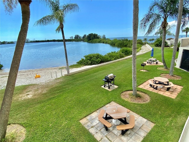 view of home's community featuring a lawn, a water view, and a patio area