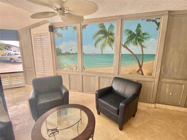 sitting room featuring ceiling fan, light tile patterned flooring, a textured ceiling, and a water view