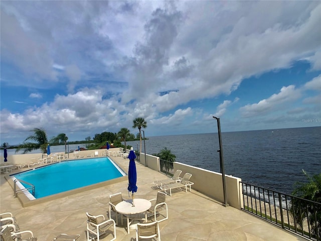 view of swimming pool with a patio and a water view