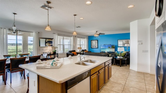 kitchen with ceiling fan with notable chandelier, a kitchen island with sink, pendant lighting, light tile patterned floors, and stainless steel appliances