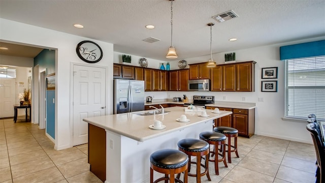 kitchen with a center island with sink, appliances with stainless steel finishes, and light tile patterned flooring