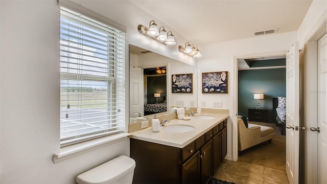 bathroom with a wealth of natural light, double sink vanity, toilet, and tile patterned flooring