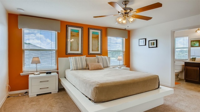 carpeted bedroom featuring connected bathroom, ceiling fan, and multiple windows