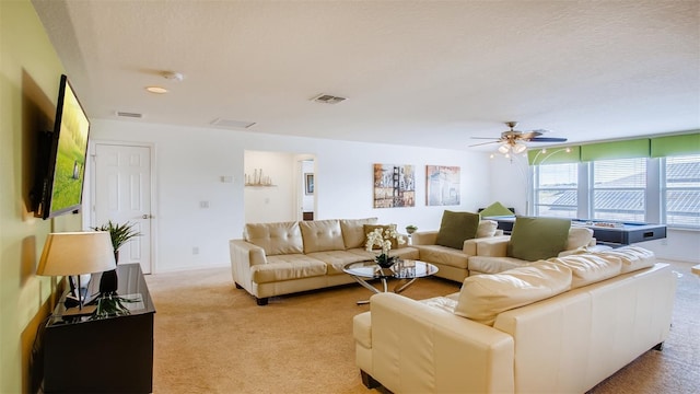 carpeted living room with ceiling fan and a textured ceiling