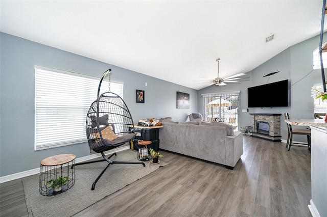 living room with ceiling fan, a fireplace, lofted ceiling, and wood-type flooring