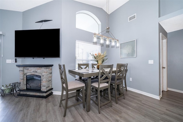 dining area with a fireplace, high vaulted ceiling, and hardwood / wood-style flooring