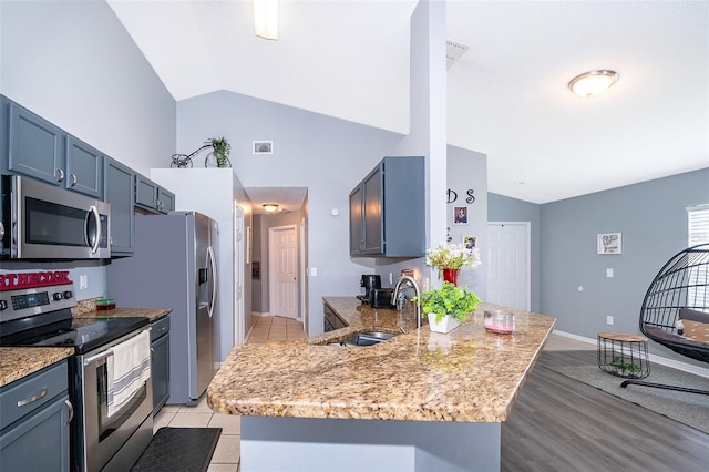 kitchen with light hardwood / wood-style flooring, light stone countertops, sink, kitchen peninsula, and stainless steel appliances