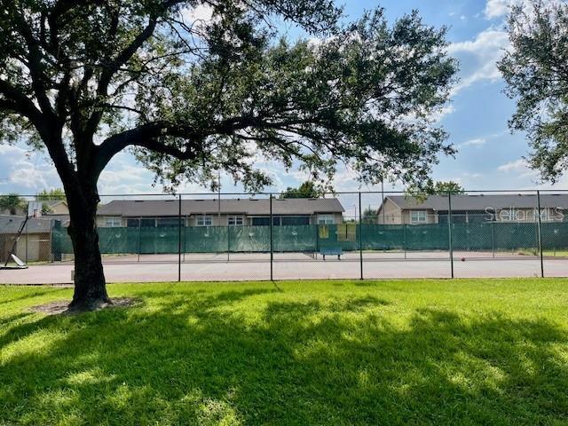 view of tennis court with fence and a yard