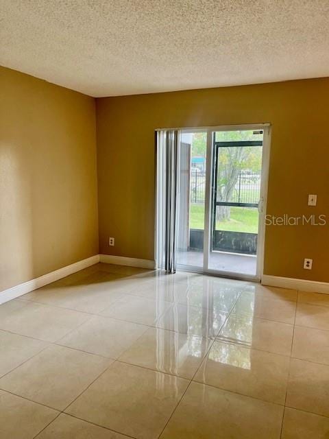 unfurnished room featuring light tile patterned floors, baseboards, and a textured ceiling