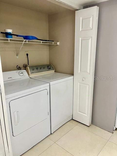 laundry area featuring laundry area, washer and clothes dryer, and light tile patterned flooring