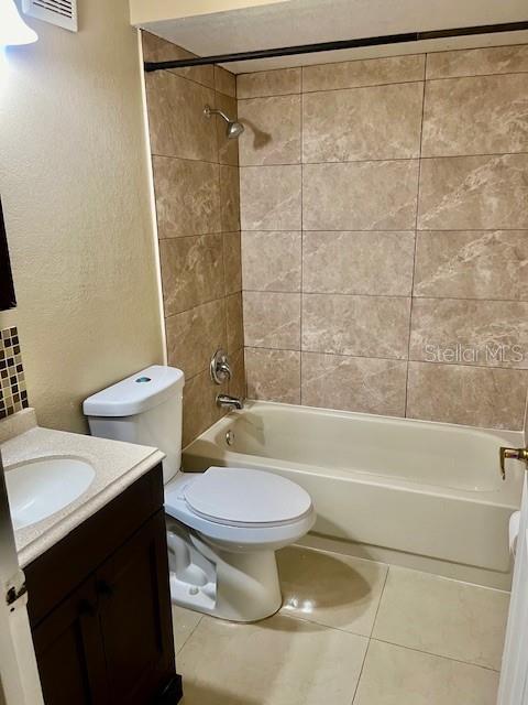 bathroom featuring tile patterned flooring, vanity, toilet, and shower / bathtub combination