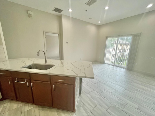 kitchen with light tile patterned flooring, sink, and light stone counters