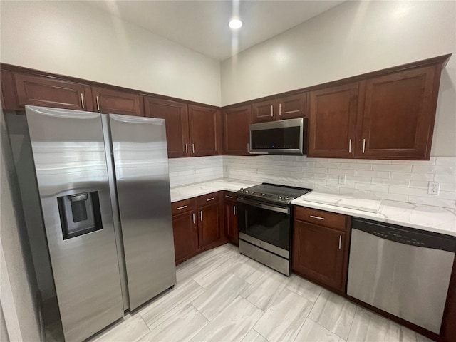 kitchen with backsplash, appliances with stainless steel finishes, and light stone countertops