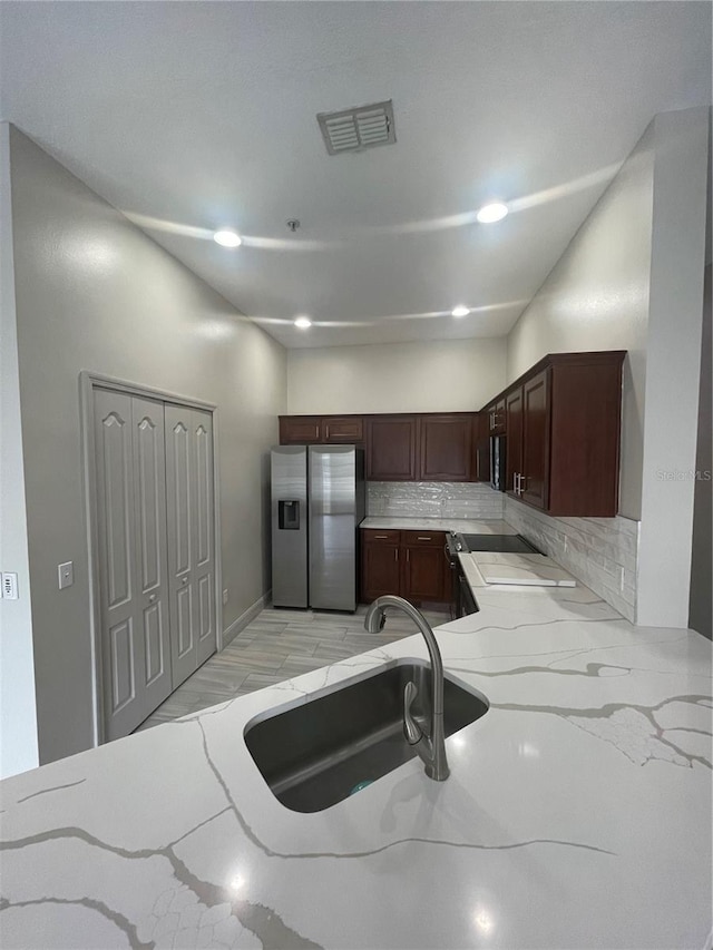 kitchen featuring light tile patterned flooring, sink, range, tasteful backsplash, and stainless steel fridge with ice dispenser