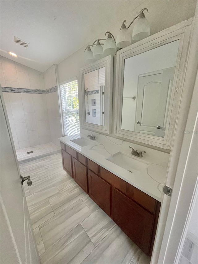 bathroom featuring tile patterned floors, double sink vanity, and a tile shower