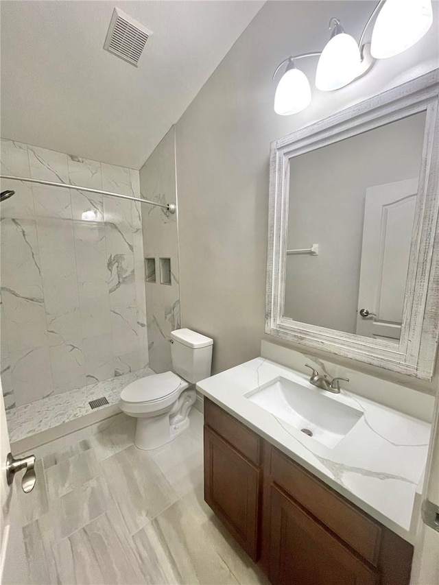 bathroom with tiled shower, tile patterned floors, toilet, and vanity