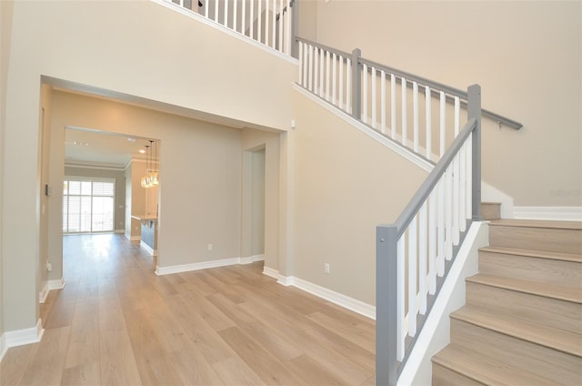 stairs featuring crown molding, hardwood / wood-style flooring, and a towering ceiling