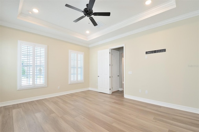 unfurnished room with ceiling fan, light hardwood / wood-style flooring, ornamental molding, and a tray ceiling