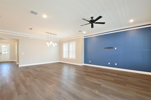 empty room featuring ceiling fan, plenty of natural light, crown molding, and wood-type flooring