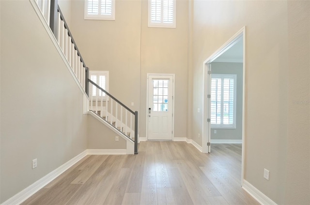 foyer entrance featuring light hardwood / wood-style floors and a towering ceiling