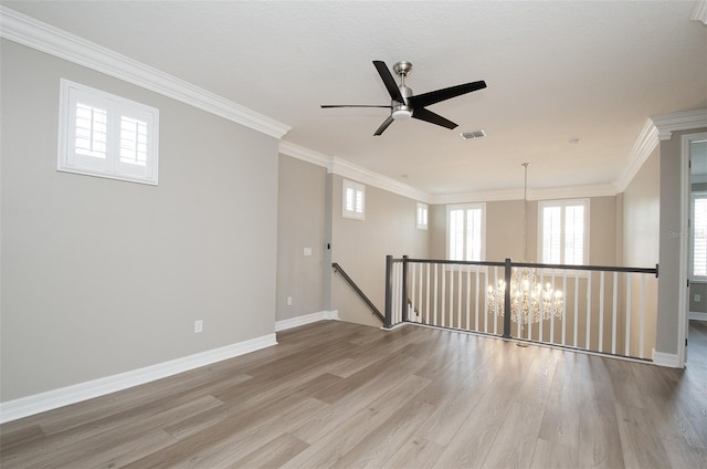 unfurnished room featuring ceiling fan with notable chandelier, crown molding, and hardwood / wood-style floors