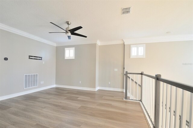 interior space featuring a textured ceiling, ceiling fan, crown molding, and light wood-type flooring