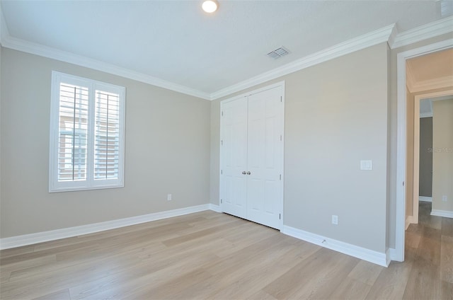 unfurnished bedroom featuring a closet, crown molding, and light wood-type flooring