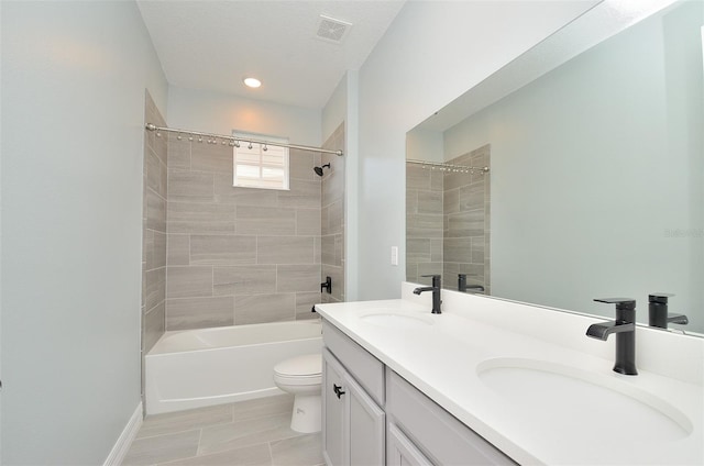 full bathroom featuring tile patterned floors, double vanity, tiled shower / bath, and toilet